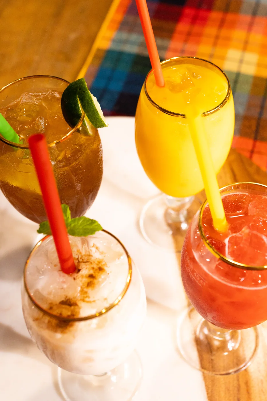 Three tall glasses of fruit juice over ice, with straws and a slice of lime.