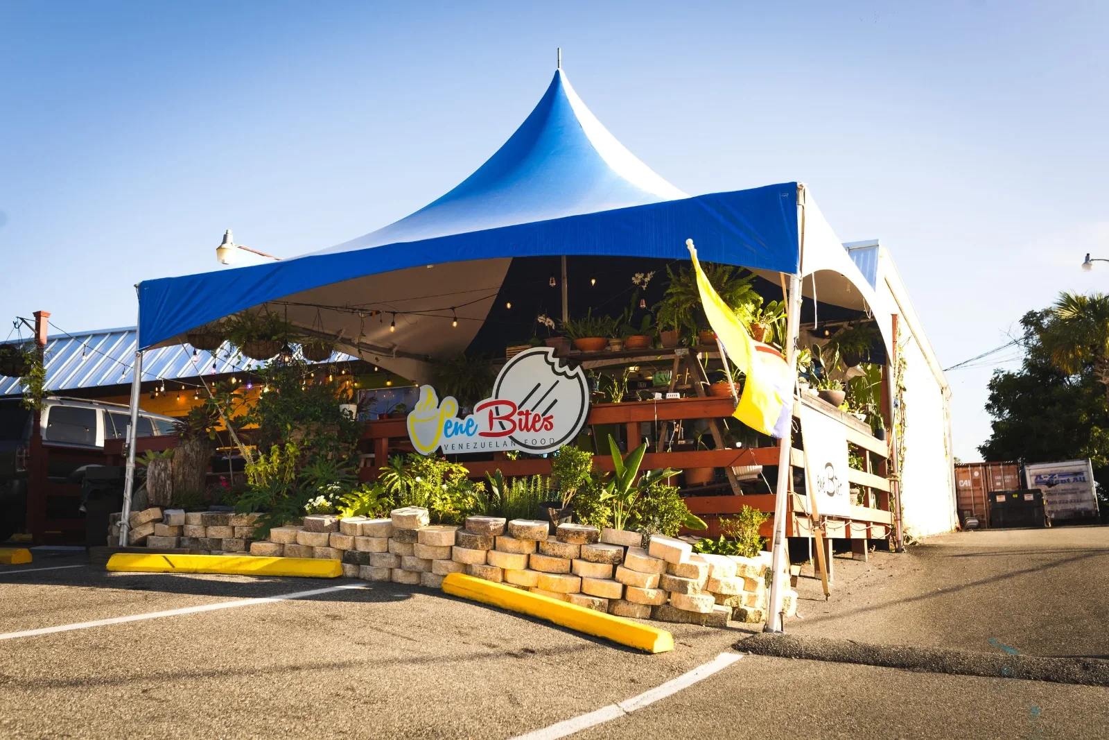 The restaurant's covered patio under a blue and white tent, with the VeneBites sign on the wall behind a low planter.